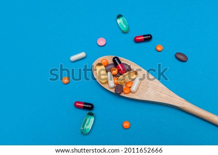 multicolored pills in a wooden spoon on a blue background