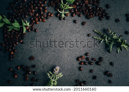 Grey grungy background with coffee beans and fresh wild mint. 
