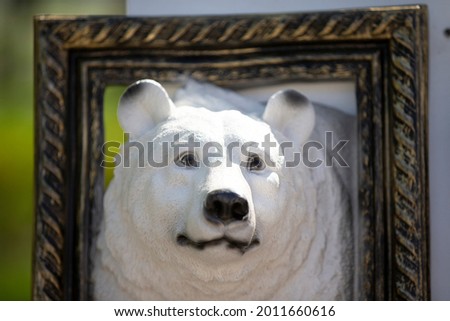 Plaster sculpture of a polar bear in a picture frame.
