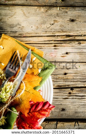 Autumn cutlery background. Fall card background for menu or invitation, banner format. With fork, knife, napkins, pumpkin, plate, multicolored leaves. On rustic old wooden table, top view copy space