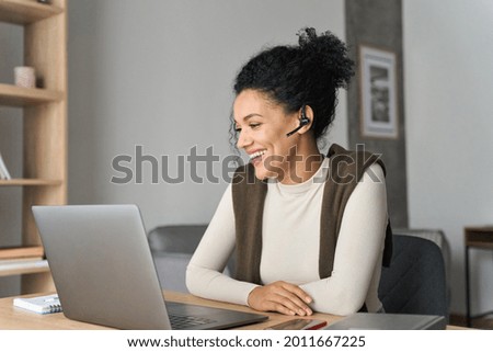 African American mixed race adult student wearing headset having virtual meeting online call with friends, educational webinar chatting at home office. Video e learning conference call on pc. Royalty-Free Stock Photo #2011667225
