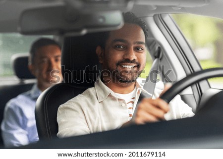 transportation, vehicle and people concept - happy smiling indian male driver driving car with passenger Royalty-Free Stock Photo #2011679114