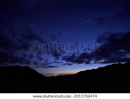Silhouette of mountains at night cloudy sky with stars