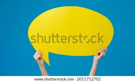 Young teen girl holding with copyspace cartoon speech bubble in hand over blue background. Copy space for place a text, message for advertisement. Advertising area, mockup promotional content.
