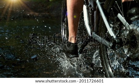 Close-up of mountain rider splashing water in river. Freeze motion of active lifestyle.