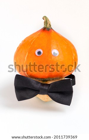 Pumpkin with eyes and the bow tie in a shape of mushroom. Thanksgiving and halloween concept.