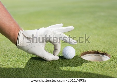 Golfer trying to flick ball into hole on a sunny day at the golf course Royalty-Free Stock Photo #201174935