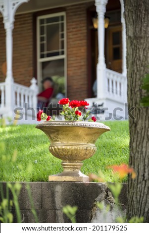 Red geraniums in an old stone pot sitting in front of a peaceful Nebraska home