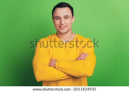 Portrait of cheerful cool guy folded arms toothy beaming smile on green background