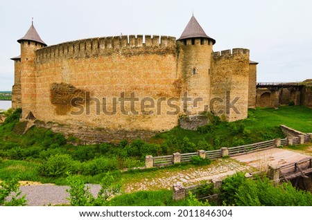 Amazing wide-angle landscape photo of medieval castle with high stone wall and towers. Blue sky background. Low perspective view. Travel and tourism concept.