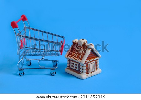 House next to a metal shopping cart on a blue background,concept of buying an apartment or house