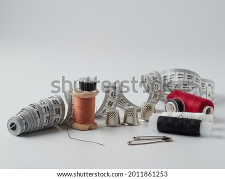 A pile of wooden buttons, a needle, old thimbles, scissors and a spool of cotton thread on a white background. The concept of needlework, sewing, tailoring    