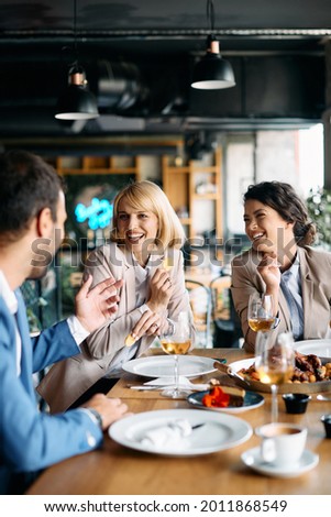 Group of happy coworkers talking and having fun while eating lunch in a restaurant. Royalty-Free Stock Photo #2011868549