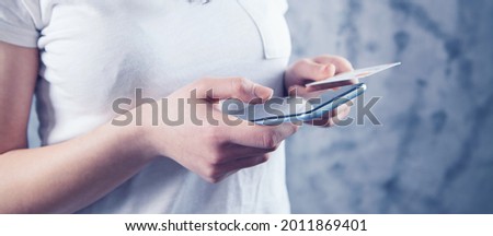 woman makes a payment by phone through a card on a gray background