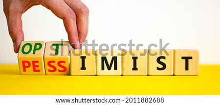 Pessimist or optimist symbol. Businessman turns cubes and changes the word 'pessimist' to 'optimist'. Beautiful yellow table, white background. Business, optimist or pessimist concept. Copy space. Royalty-Free Stock Photo #2011882688