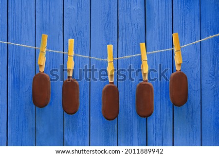 lot of chocolate ice creams hanging on rope near deep blue background. hot summer tasty dessert and delicious chilling food concept