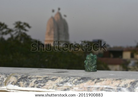 Green aventurine lord Ganesha with blurred temple background kept on the terrace in sunlight