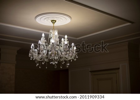 Glass chandelier. Ceiling light source. Lamps shine through a vintage chandelier. Royalty-Free Stock Photo #2011909334