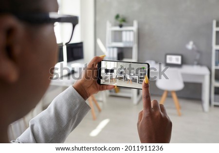 Black designer taking office interior photos, making presentation or video calling client using smart phone app. Rental agent or realtor shows work space while giving tour around display apartment Royalty-Free Stock Photo #2011911236