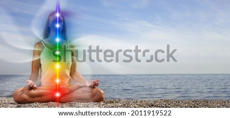 Yoga meditation outdoors. Glowing seven all chakra. Woman sits in a Upward Salute pose on beach sunset view, Kundalini energy. girl practicing. Royalty-Free Stock Photo #2011919522