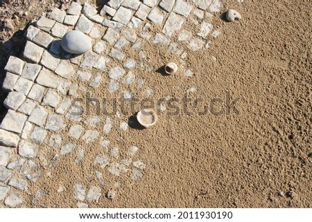 close up of white stone slabs formed into a mosaic covered with beach sand and seashells. Broken tiles mosaic seamless pattern, real photo or brick seamless and texture interior background.
