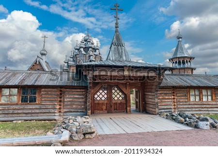 a picturesque wooden gate leading to a historic wooden church in the suburbs of the Russian city of St. Petersburg against the background of a blue cloudy sky