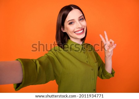 Photo of cool brunette hairdo millennial lady do selfie show v-sign wear green shirt isolated on orange color background