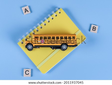 School bus, notebook and wooden cubes with letters on a blue background, top view close-up.