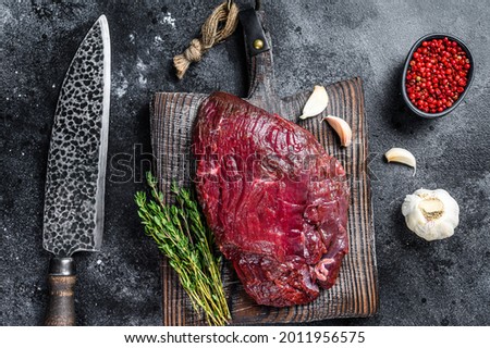 Venison raw deer meat on a cuuting board with herbs. Black background. Top view Royalty-Free Stock Photo #2011956575