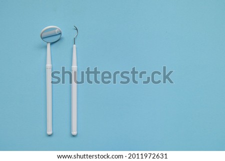 Dentist tools, Dental Mirror, Dental Scaler. Dentist equipment on blue background Royalty-Free Stock Photo #2011972631