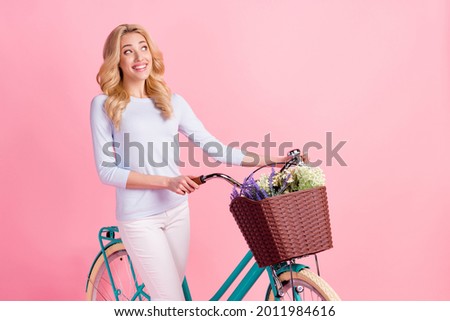 Full body photo of charming dreamy young woman look empty space ride bike isolated on pink color background