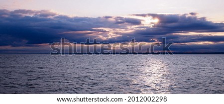 Sunset through clouds, where the horizon meets calm waters. Pastel tones and the peaceful feel of eternity.  Long Island Sound, between Connecticut and New York State's Long Island.