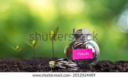 Plant growing in Coins glass jar on dry for travel  together and success.  Saving paper label for money planning future travel. Green nature background