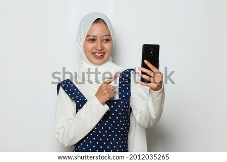 happy young asian muslim woman using mobile phone isolated on white background

