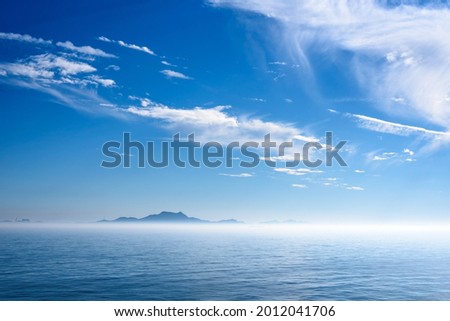 Sea landscape, sea surface. Blue sky, clouds, sunlight, rays. Empty natural scene in the open air. Blurred abstract background. Background of a sea landscape. Blue sky with clouds over the sea.