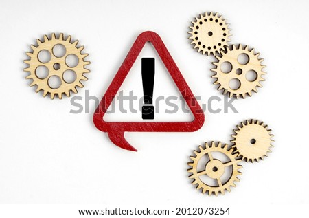 Business and finance concept. Near the gears lies a triangular plate inside which is a exclamation mark