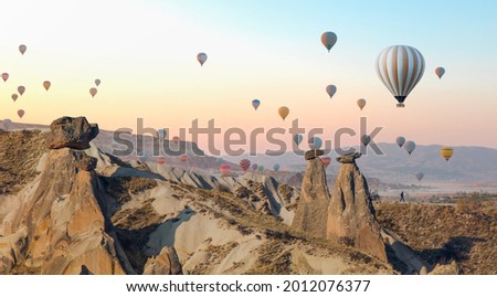Hot air balloon flying over fairy chimneys and rock landscape at Cappadocia Turkey Royalty-Free Stock Photo #2012076377