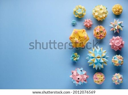 Set of multicolor handmade modular origami balls or Kusudama Isolated on blue background. Visual art, geometry, art of paper folding, paper crafts. Top view, close up, selective focus, copy space.