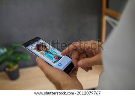 Dating online. Man looks through a photo of a young African American woman on his smartphone, clicks I like it. Modern communication at a distance, electronic photos, social networks, communication.
