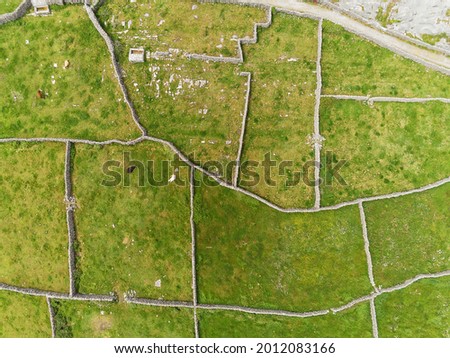 Aerial view on stone fences and green fields of Aran islands, county Galway, Ireland. Warm sunny day. Unique maze of hand made dry stone wall. Irish scenery and landscape