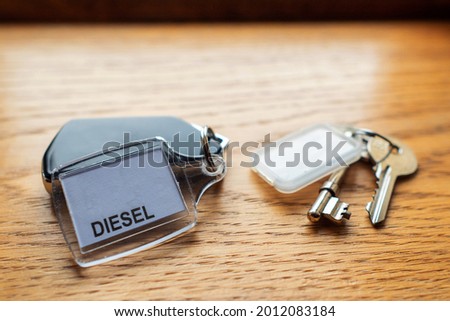 Car key remote and tag with diesel fuel sign on it and a simple keys to a hotel room on a wooden surface. Travel in rented car concept