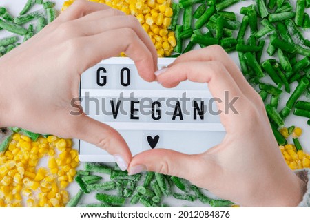 Lightbox with text GO VEGAN frozen vegetables food of yellow corn, green beans. Harvest Food preservation for winter. Copy space