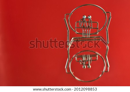 Beautiful closeup view of metal souvenir of couple sitting on a bench or swing on red reflective background. Love and affection concept. Copy space