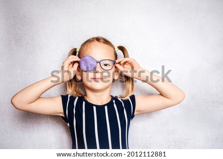 Happy little girl wearing glasses and eye patch or occluder, amblyopia (lazy eye) treatment Royalty-Free Stock Photo #2012112881