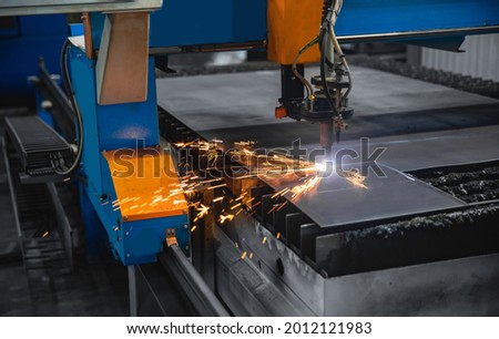 Plasma cutting CNC machine cuts metal material with sparks, industry background aerospace. Royalty-Free Stock Photo #2012121983