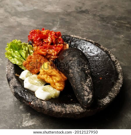 Picture of spicy chicken, in Indonesia named it Ayam Geprek, served in a stone mortar, concrete floor as background 