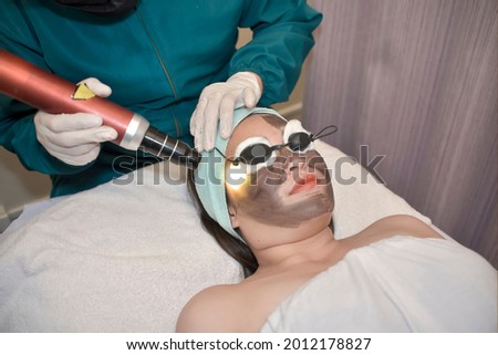 A young asian lady undergoes a laser carbon peel procedure at a skin or dermatologist clinic. Royalty-Free Stock Photo #2012178827