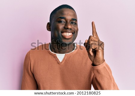 Young african american man wearing casual clothes pointing finger up with successful idea. exited and happy. number one. 