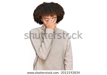 Young hispanic girl wearing wool winter sweater tired rubbing nose and eyes feeling fatigue and headache. stress and frustration concept. 