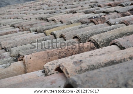 Old roof top made of terra cotta tiles in shades of pink and grey. Can be used as background. Royalty-Free Stock Photo #2012196617